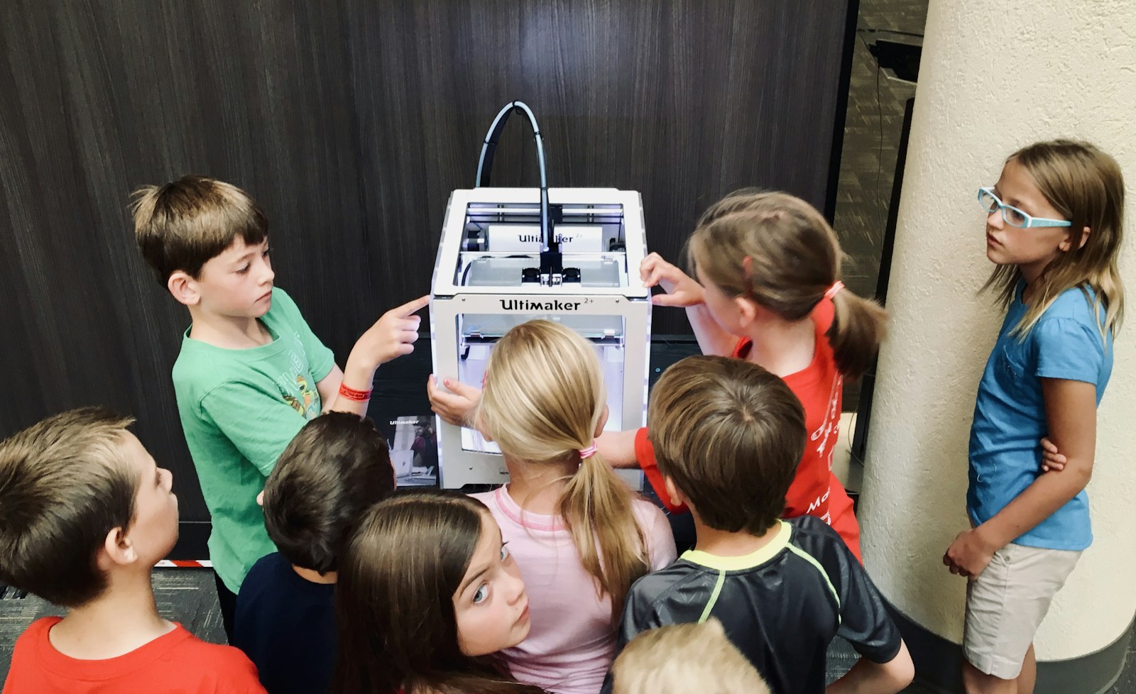 Kids crowded around a 3D printer in a classroom lab
